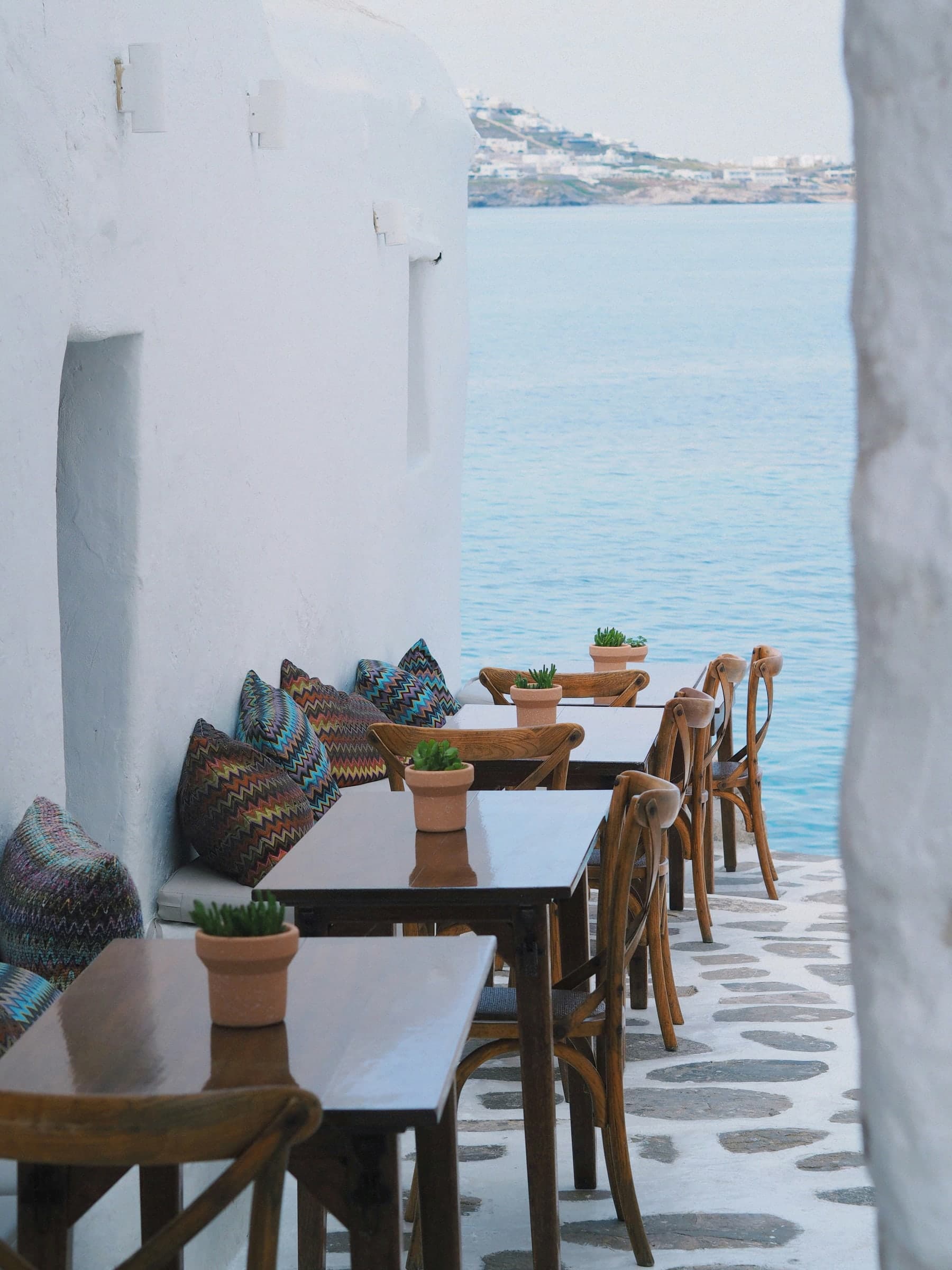 Wooden tables on a white terrace over the sea