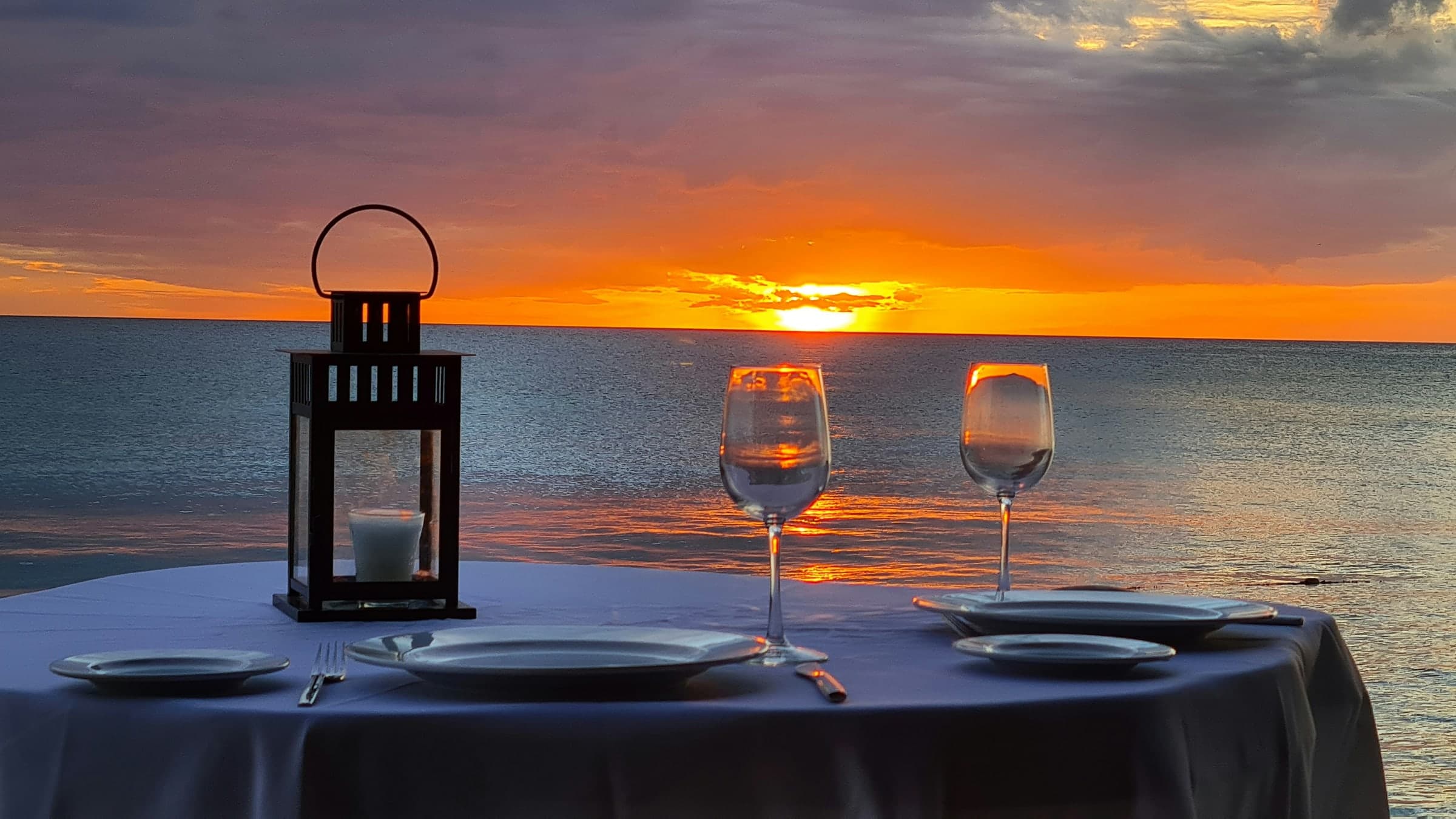 A table set for dinner beside the sea at sunset
