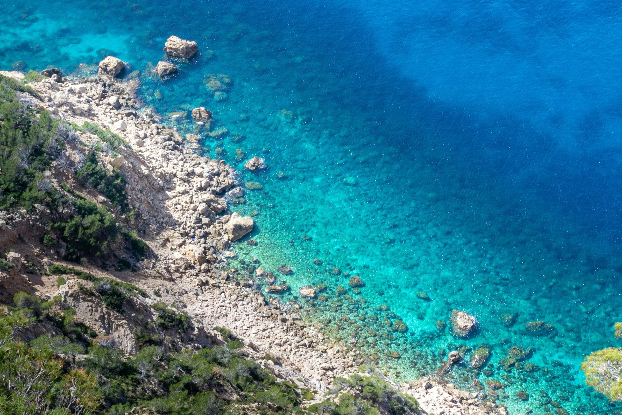 Clear turquoise water along a rocky shore, seen from above