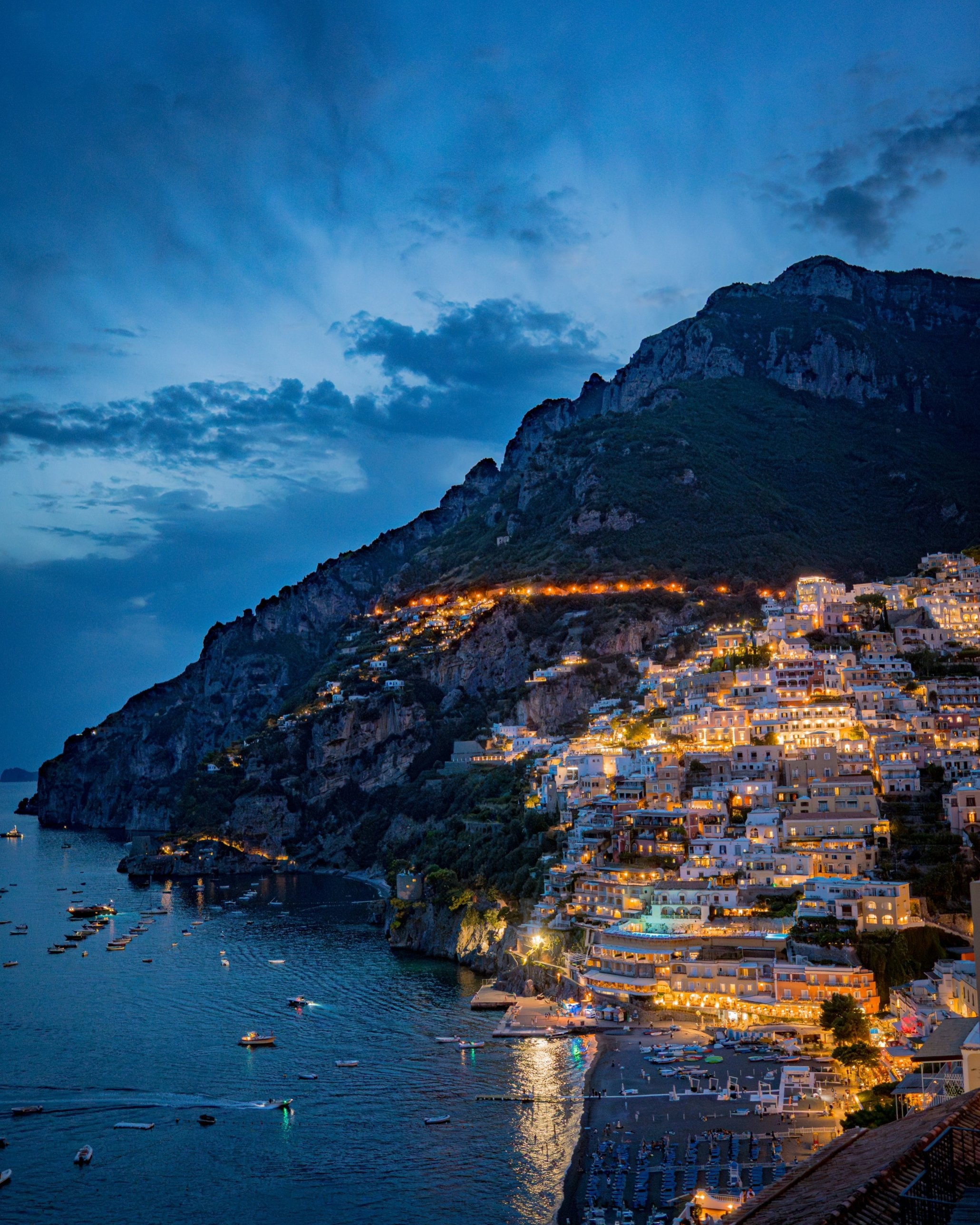 Positano lit up at dusk above the sea